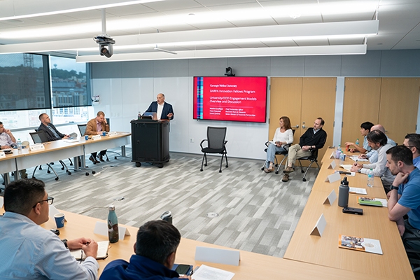 A man speaks to a group of people all seated in a u-shape