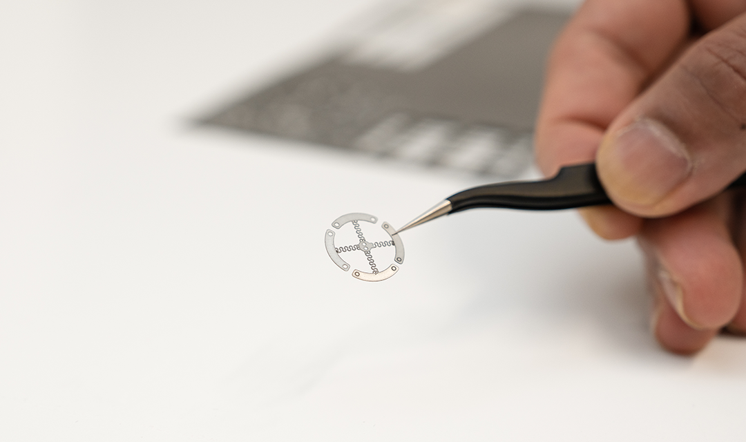 A circular metal wearable with an x in the middle
