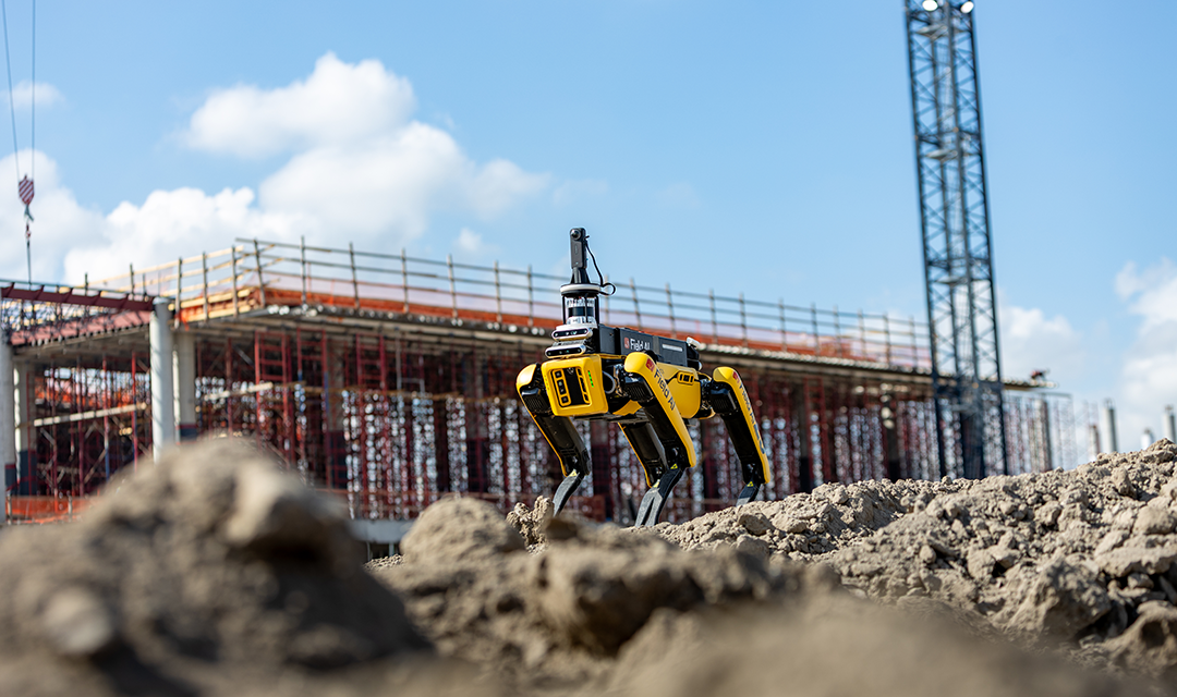 A yellow four-legged robot on a construction site