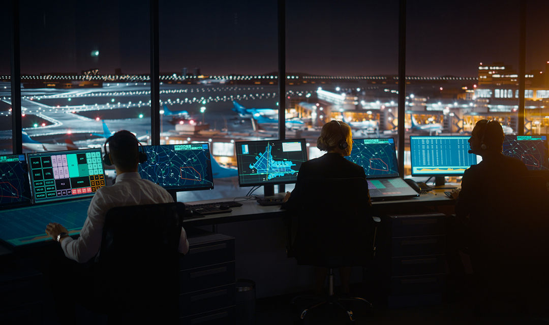 Stock image of air traffic controllers in tower at night