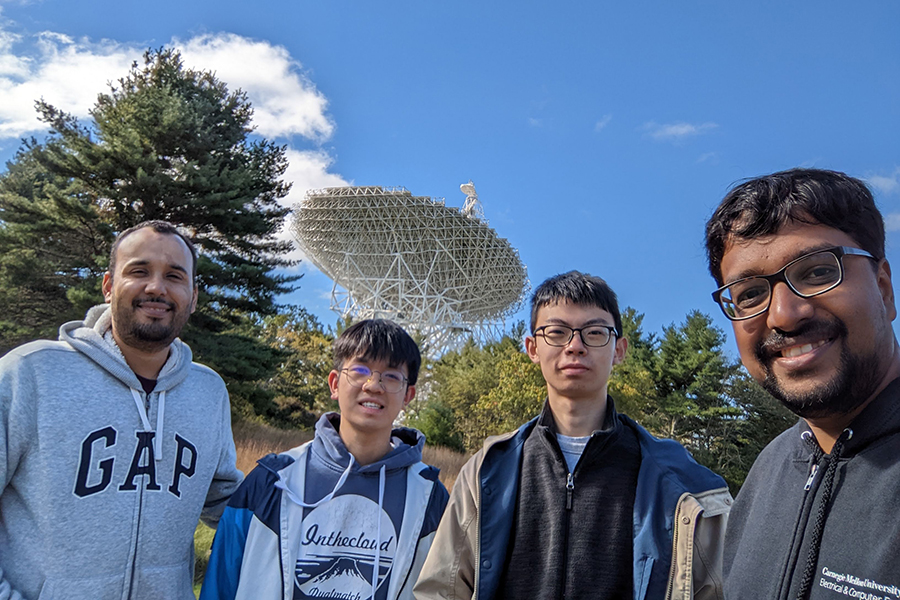 Four men in front of a radio telescope dish