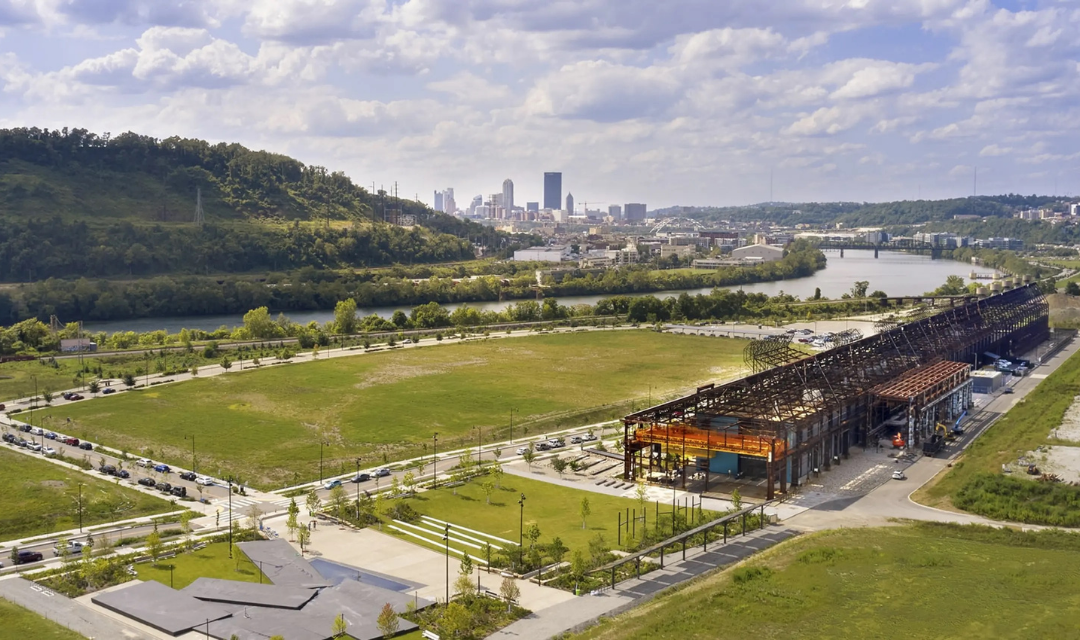 An aerial view of a warehouse on the river with Pittsburgh in the background