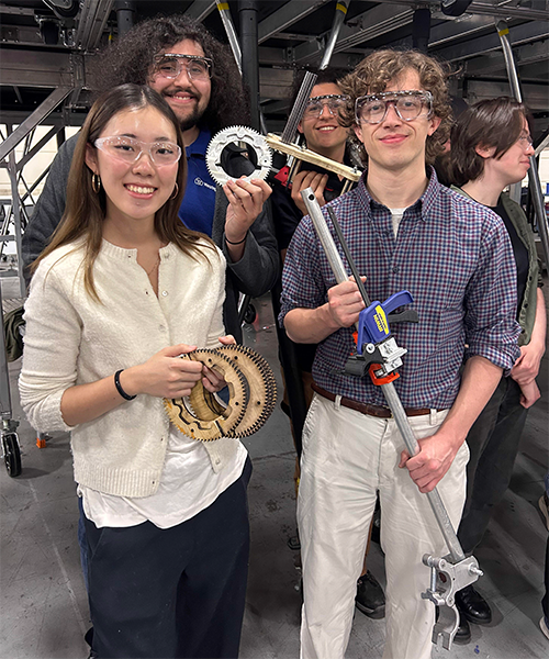 Four students holding different mechanical parts