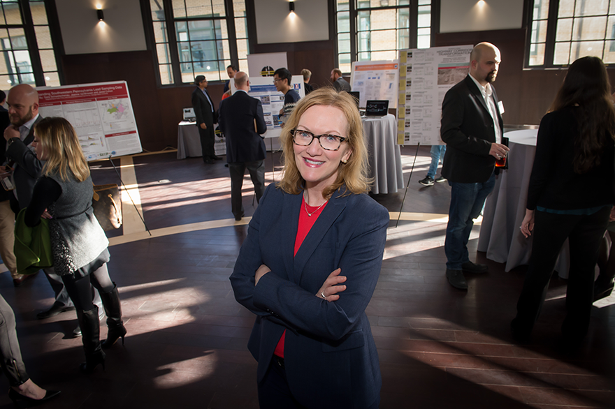 A woman in a suit with a red shirt. She's attending a poster session.