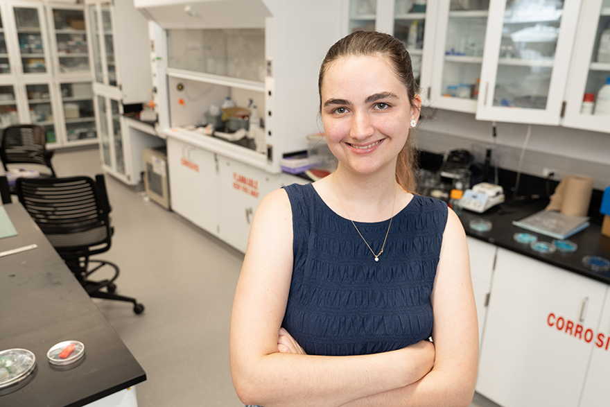 Charlotte Betz with her arms crossed in a lab with petri dishes and scales