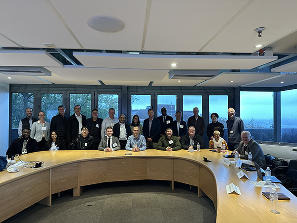 Group of professionals posing for a photo in a modern conference room with a large curved meeting table and wide windows in the background.