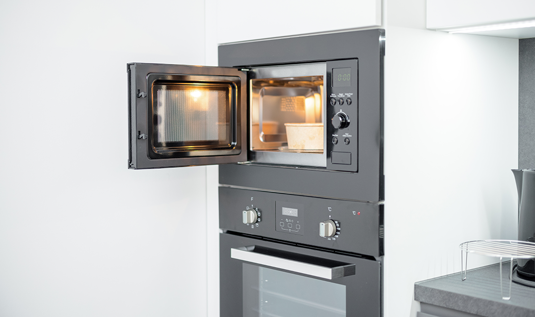 A microwave with the door open and a takeout container inside