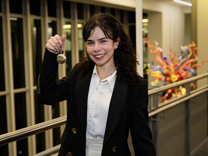 A woman holding up a medal and smiling