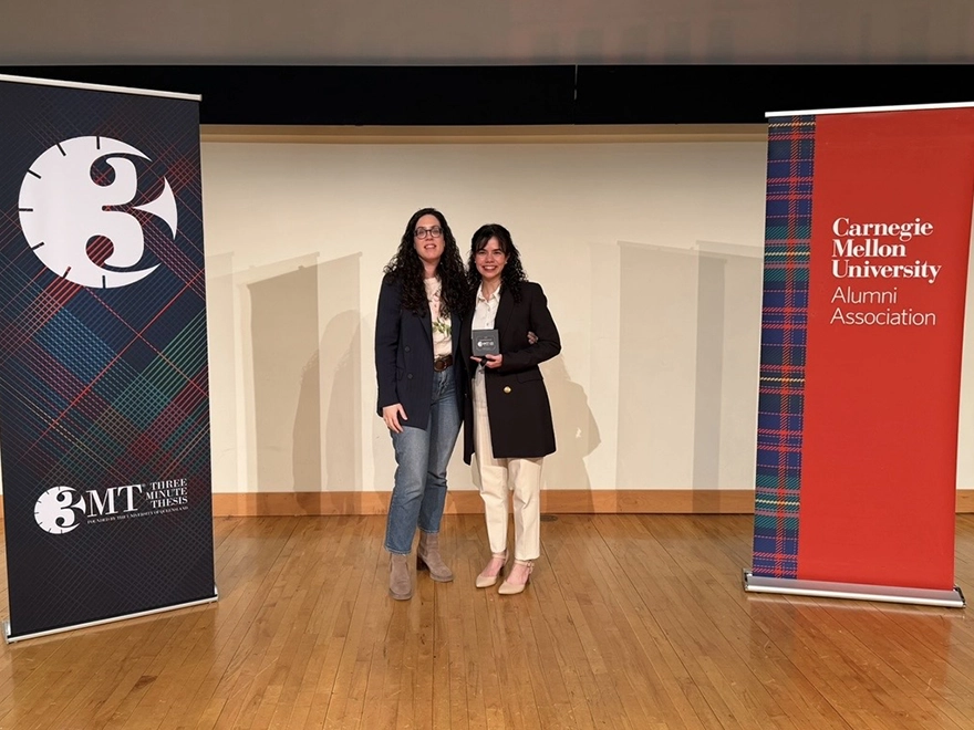 Two women stand between two upright banners