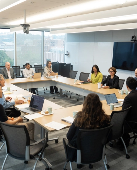 A group of people sit around a conference table talking