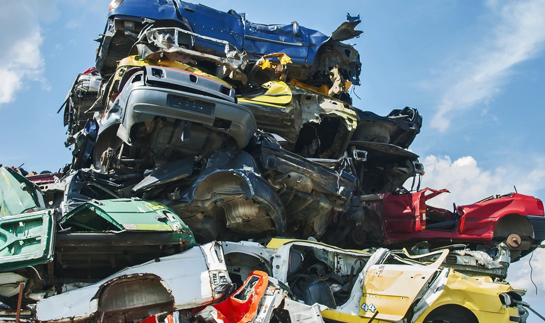 Damaged cars in a variety of colors stacked on top of each other
