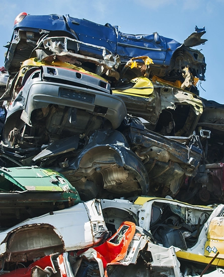 Damaged cars in a variety of colors stacked on top of each other