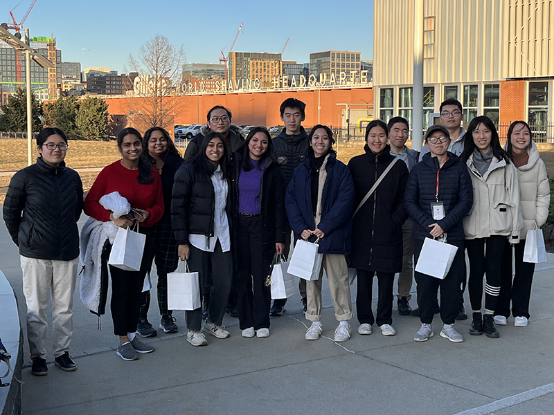 A group of students holding white bags outside