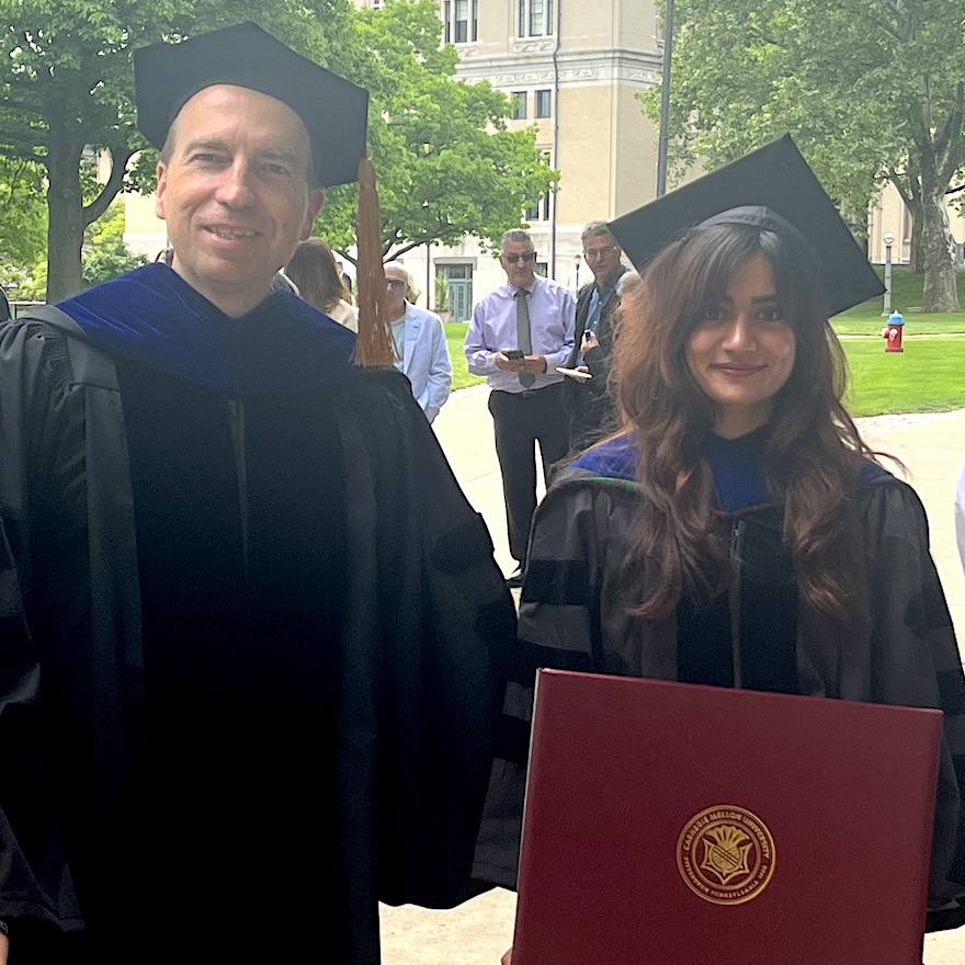 Michael Bockstaller and Ayesha Abdullah wearing caps and gowns outside on CMU campus