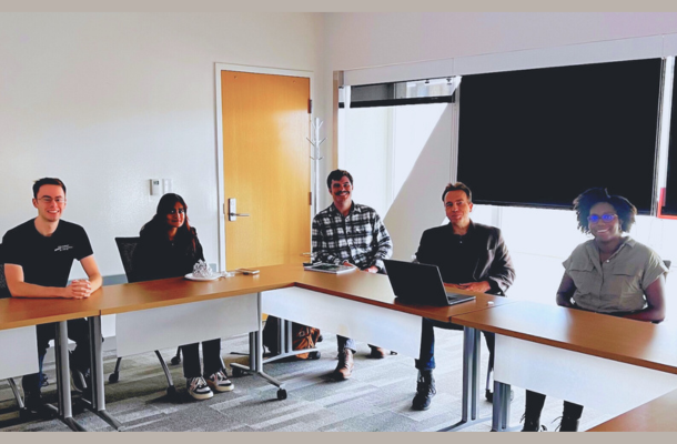 students sitting around table with screens in background