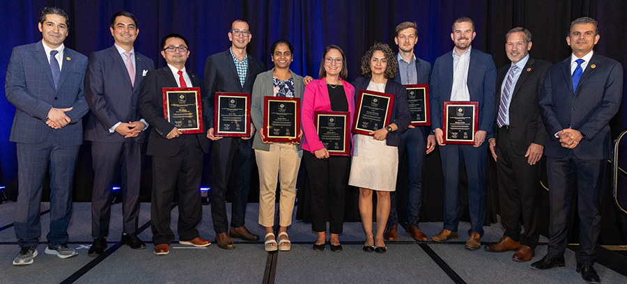 The awardees (a dozen people) standing on stage holding their awards