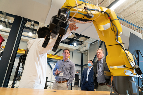 A researcher showing partners a robotic arm