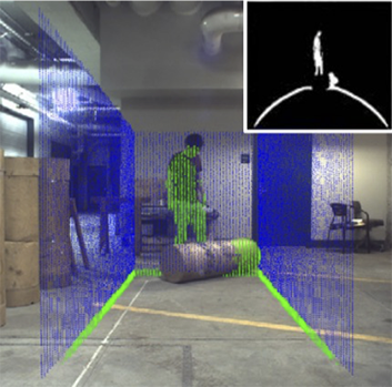 A human stands in a room with a large piece of material. A computer simulation reads the situation in blue and green and maps the area.