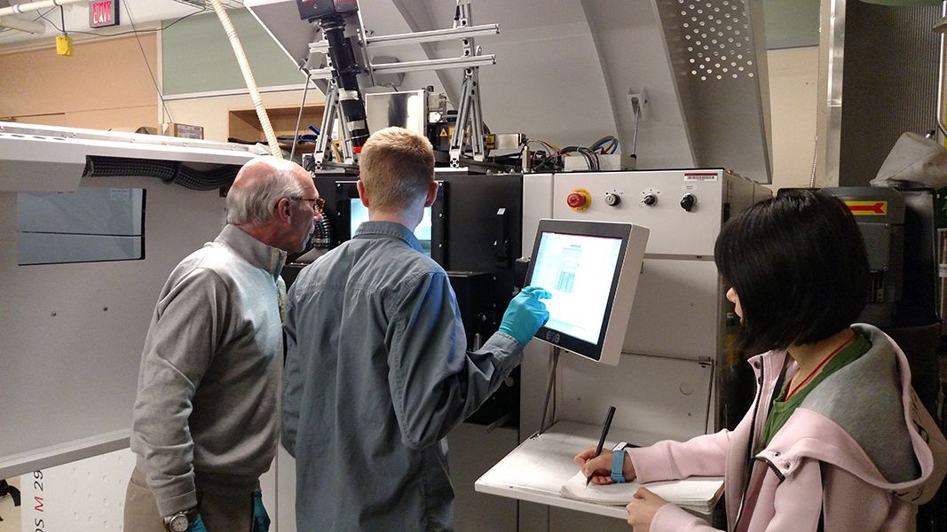 Three people working on a screen in a lab