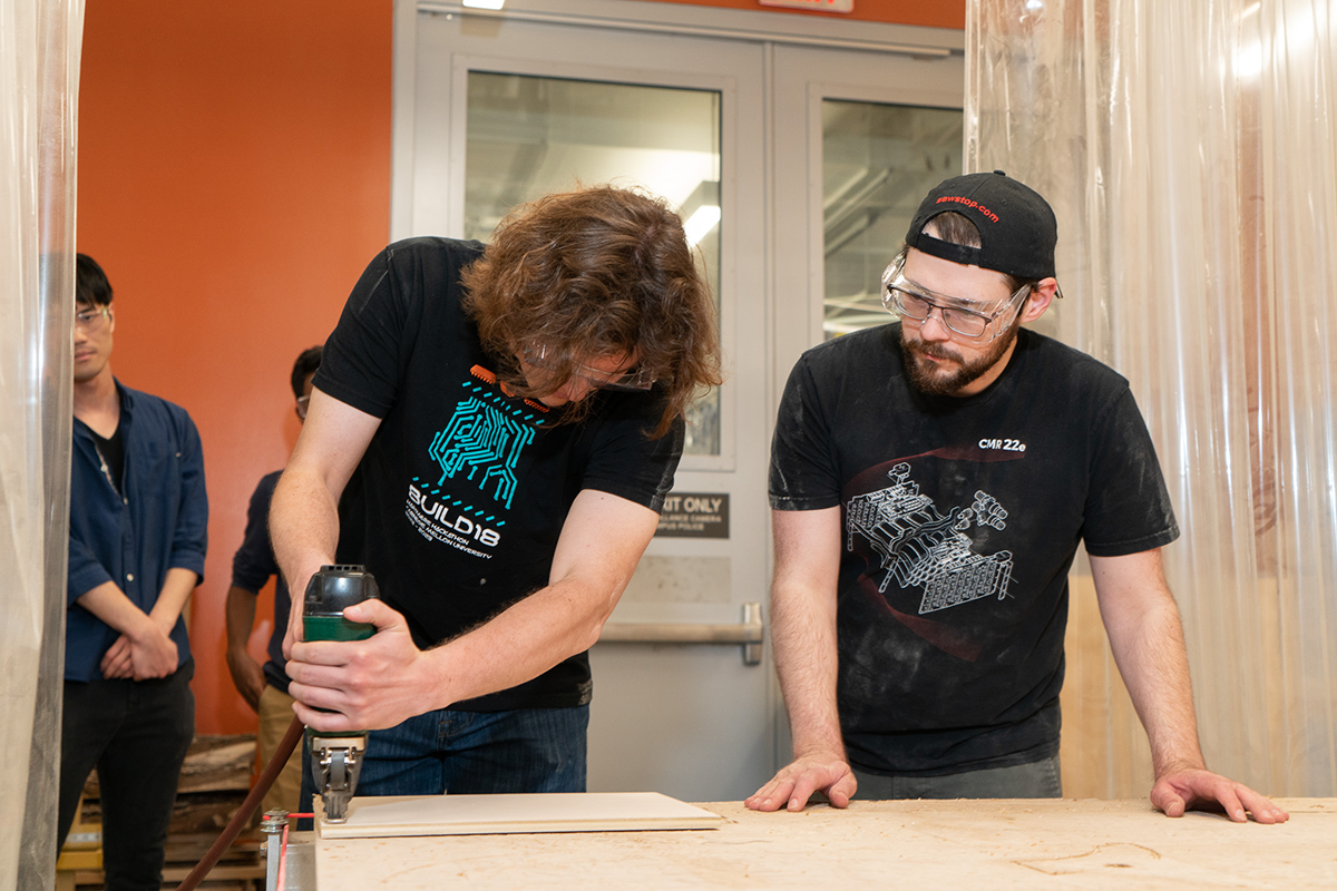 student works with instructor in woodshop